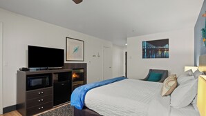 A bedroom with a bed, a television, a fireplace, and artwork on the walls. - Sunset Haven (Depoe Bay)