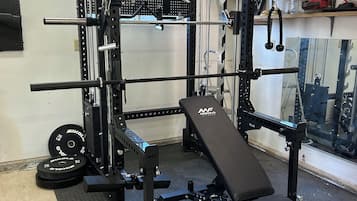 Ein Fitnessraum mit einem Squat-Rack, einer Bankpresse und Gewichtsplatten.