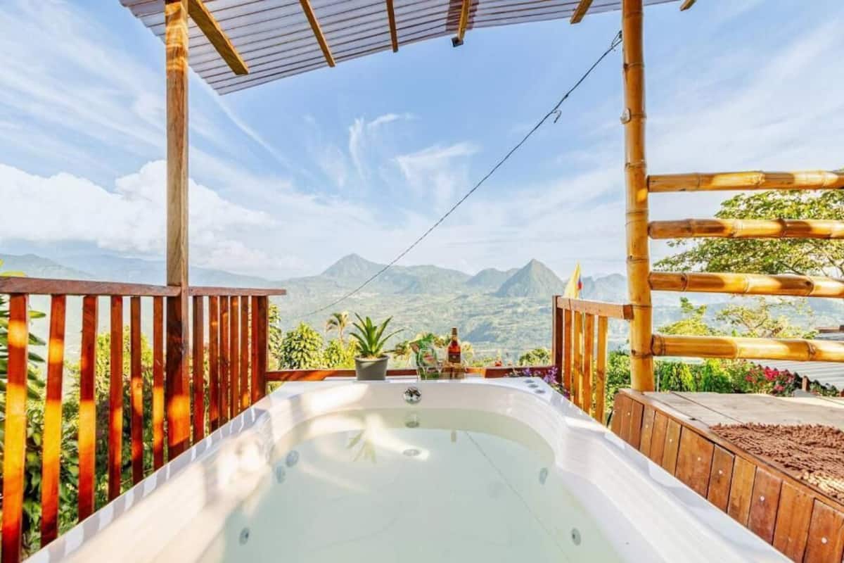 Un jacuzzi con vista a la montaña, rodeado de barandas de madera y plantas en macetas.