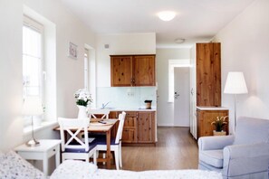 A compact living space with a dining area, kitchenette, and a seating area with a lamp. - 3-person Holiday Apartment With Balcony (Krokowa)