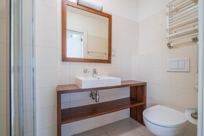 A bathroom with a wooden vanity, a white sink, a mirror, and a toilet. - 3-person Holiday Apartment With Balcony (Krokowa)