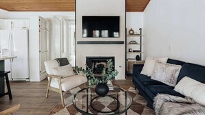 A living room with a fireplace, a sofa, a chair, and a coffee table. - Bearfoot Lake Escape (Big Bear Lake)