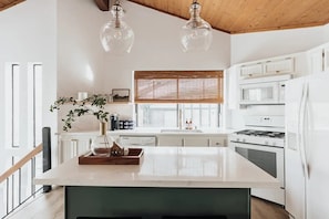 Una cocina moderna con armarios blancos, una isla central, una estufa y un refrigerador.