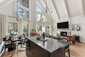 A spacious kitchen with a large island, dining area with chairs, and a living room with a fireplace. - A-Frame in Moonridge, Big Bear Lake - A/C, Hot Tub (Big Bear Lake)
