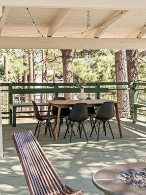Eine Terrasse im Freien mit Holztisch und -stühlen, einer Bank und einem Feuerkorb.
