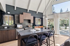 A modern kitchen with a large island, dark cabinetry, and a view of the outdoors. - A-Frame in Moonridge, Big Bear Lake - A/C, Hot Tub (Big Bear Lake)
