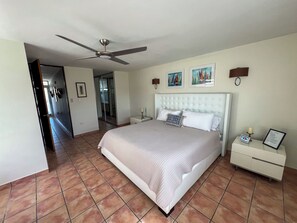 A bedroom with a bed, a ceiling fan, a nightstand, and a door leading to another room. - Villa Merchán (Dorado)