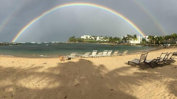 A beach with lounge chairs, a clear sky, and a rainbow. - Villa Merchán (Dorado)