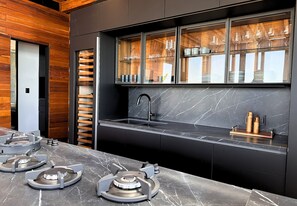 A modern kitchen with a built-in stove, a large window with glassware, and a marble countertop. - Apartamento con jacuzzi privado en ZR (Puerto Vallarta)