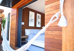 A hammock, a wooden wall, a bed, and two framed artworks in a room. - Apartamento con jacuzzi privado en ZR (Puerto Vallarta)