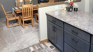 Cucina con zona pranzo, sedie di legno, piano di lavoro in granito e uno specchio.