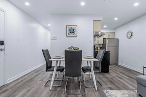 A modern dining area with a table, chairs, and a kitchen in the background.