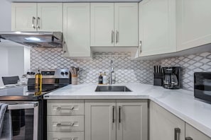 A modern kitchen with a stove, oven, sink, and cabinets.