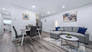 Un salon moderne avec un canapé gris, une table basse et un coin repas comprenant des chaises et une table.