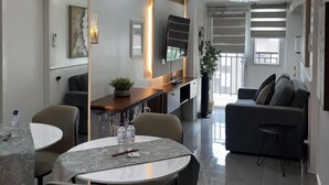 Una sala de estar moderna con comedor, un sofá, un televisor y un ventanal grande.