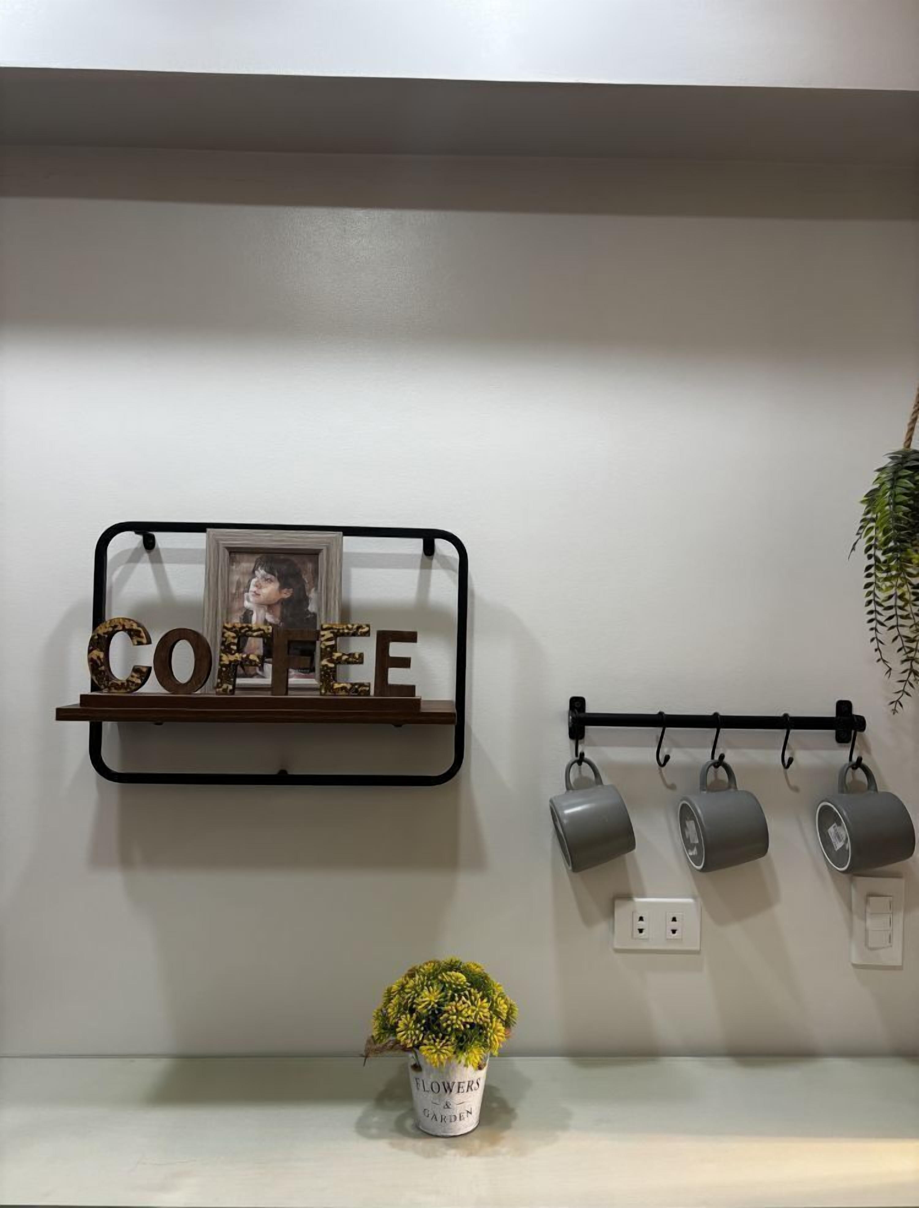 Une étagère murale sur laquelle est écrit le mot « CAFÉ » et qui porte un cadre photo.