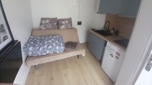 A compact room with a bed, a small kitchenette, and a door. - Cosy mini studio in Montmartre (Paris)