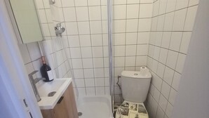 A small bathroom with a shower, toilet, and sink. - Cosy mini studio in Montmartre (Paris)