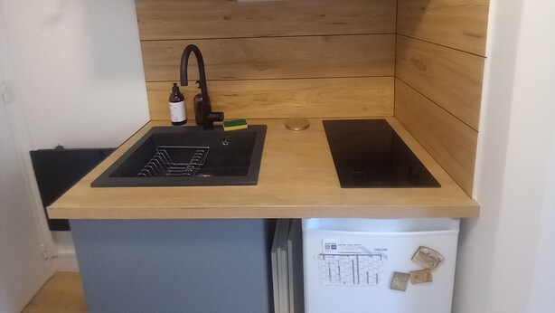 A compact kitchen with a built-in sink, a dishwasher, and wooden cabinetry. - Cosy mini studio in Montmartre (Paris)
