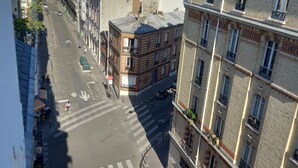 A street view with buildings, a crosswalk, and parked motorcycles. - Cosy mini studio in Montmartre (Paris)