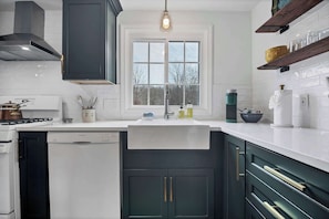 A modern kitchen with a Bosch dishwasher, a window above the sink, and wooden shelves above the countertop.