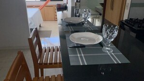 Un comedor con encimera negra, un plato blanco, una copa y una silla de madera.