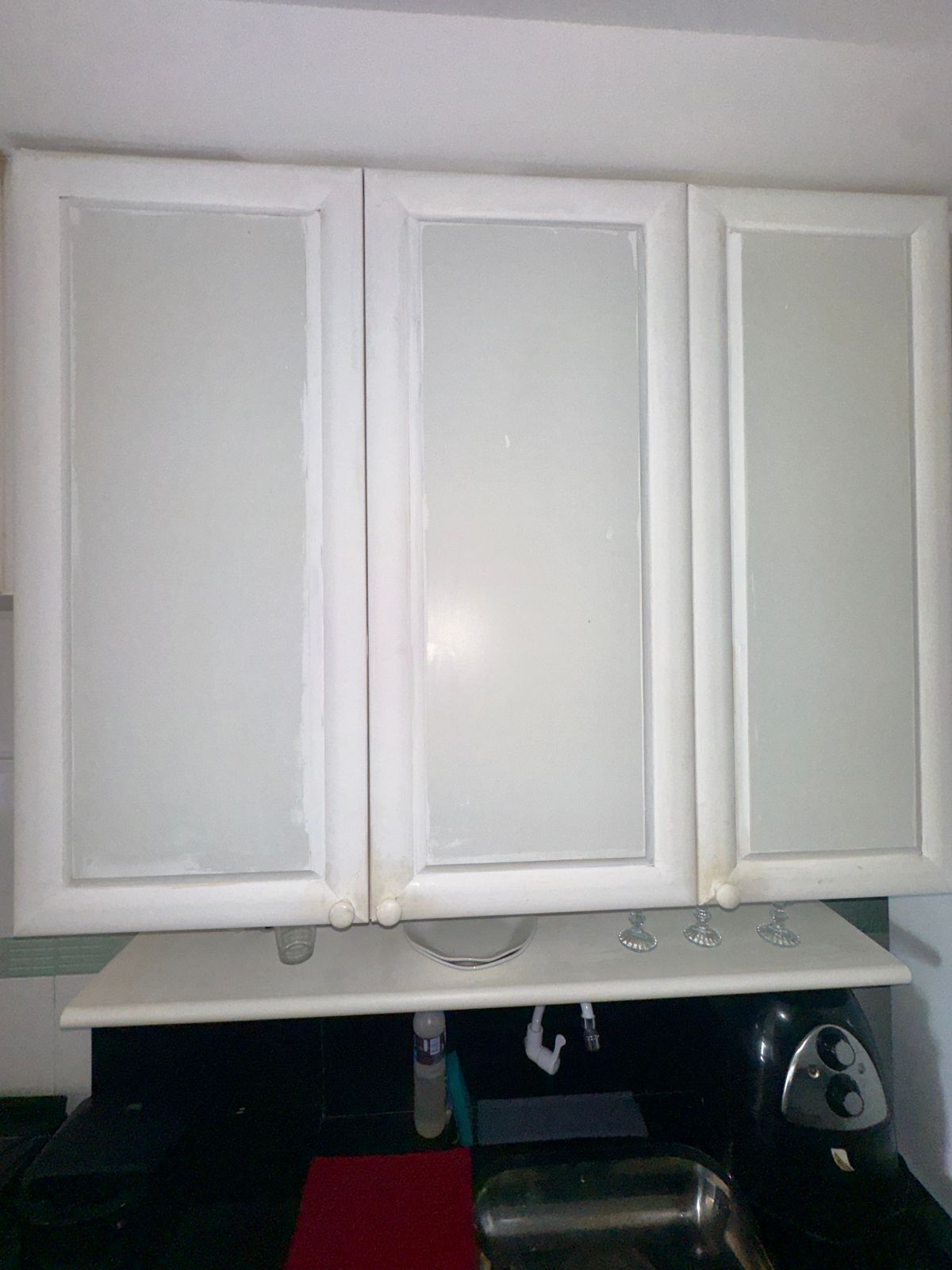Una cucina con mobili bianchi, un piano di lavoro rosso e un lavello.