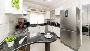 A modern kitchen with a stainless steel refrigerator, a built-in oven, and a ceiling fan. - Stay House - Pousada boutique (Joinville)