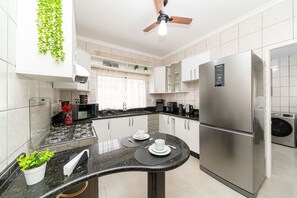 Eine moderne Küche mit einem Edelstahl-Kühlschrank, einem Einbauofen und einem Deckenventilator.
