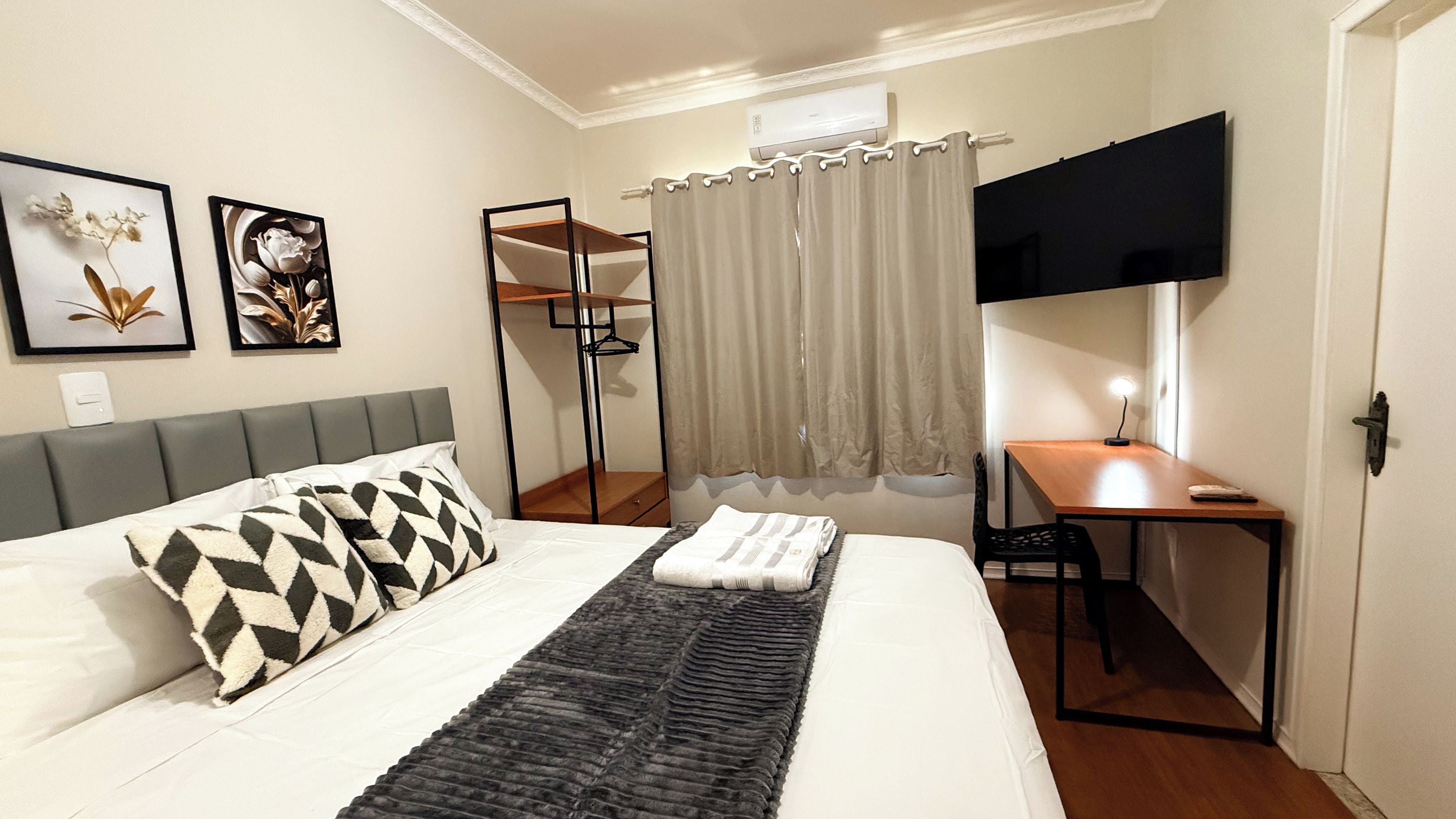 A hotel room with a bed, a desk, a television, and a mirror.