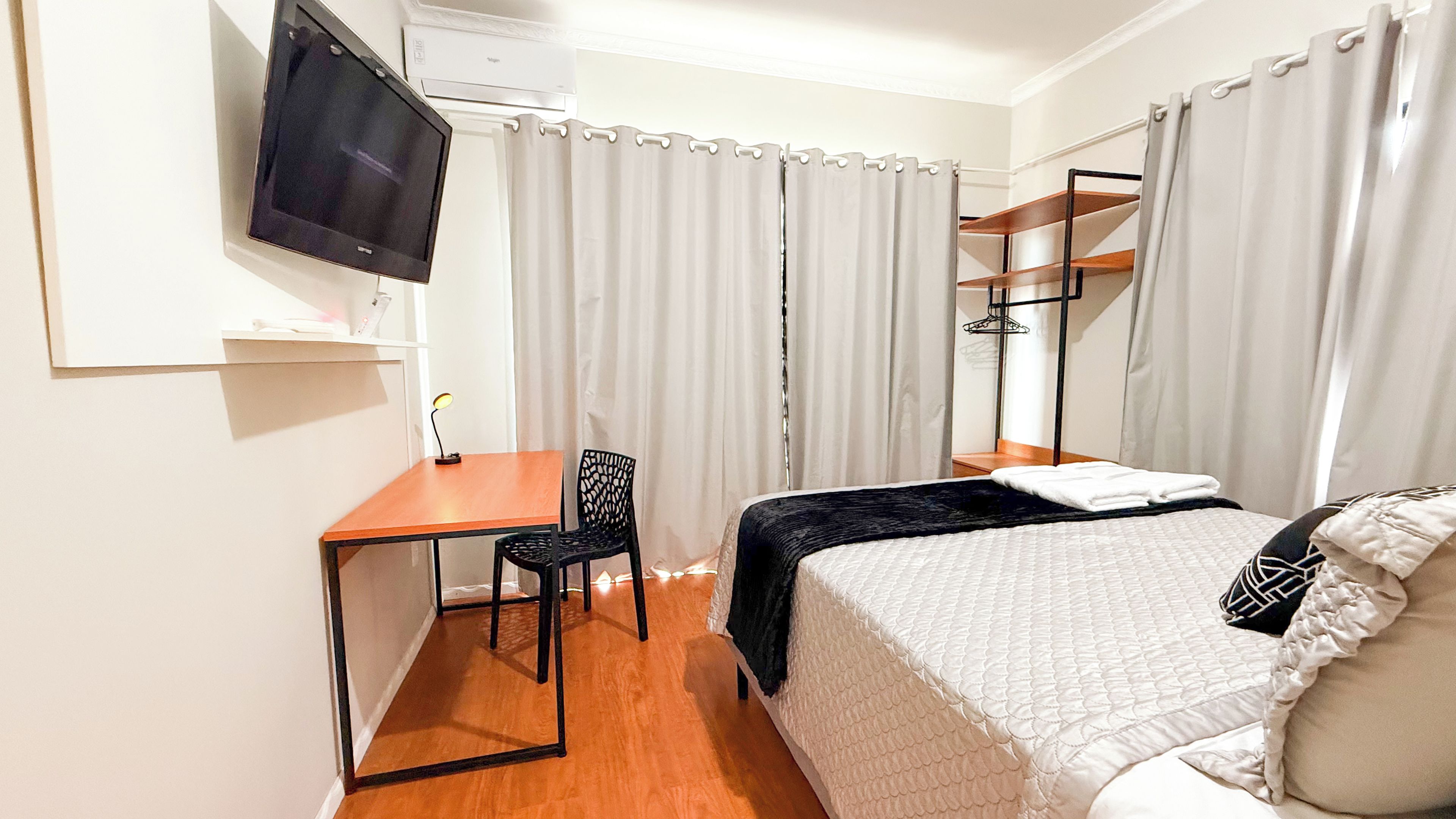 Une chambre d’hôtel équipée d’un lit, d’un bureau, d’une chaise, d’une télévision et d’une armoire.