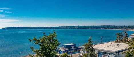 Blick auf die Küste mit blauem Himmel, einem Yachthafen und modernen Gebäuden mit flachem Dach.