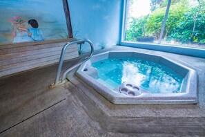 Een bubbelbad met een metalen trap, een houten bank en een muurschildering.
