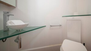 A bathroom with a glass sink, a white toilet, and a glass shelf above the toilet. - Two bedroom apartment Uptown Barcelona (Barcelona)