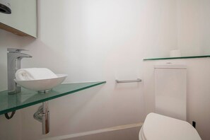 A bathroom with a glass sink, a white toilet, and a glass shelf above the toilet. - Two bedroom apartment Uptown Barcelona (Barcelona)