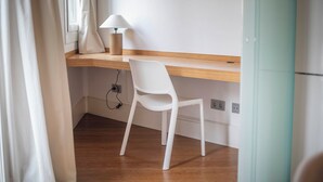 A room with a wooden desk, a white chair, a lamp, and a window with curtains. - Two bedroom apartment Uptown Barcelona (Barcelona)