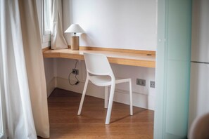 A room with a wooden desk, a white chair, a lamp, and a window with curtains. - Two bedroom apartment Uptown Barcelona (Barcelona)