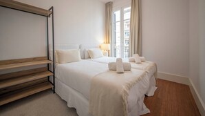 A hotel room with a bed, bedside tables, a lamp, and a view of the outside. - Two bedroom apartment Uptown Barcelona (Barcelona)