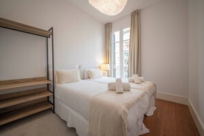 A hotel room with a bed, bedside tables, a lamp, and a view of the outside. - Two bedroom apartment Uptown Barcelona (Barcelona)