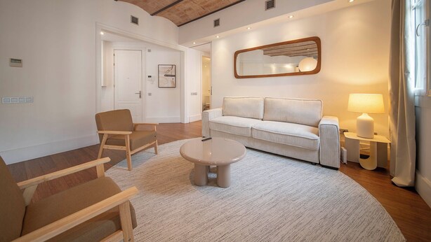 A modern living room with a sofa, armchairs, a coffee table, and a lamp. - Two bedroom apartment Uptown Barcelona (Barcelona)