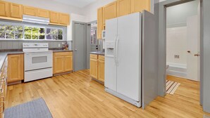 Eine moderne Küche mit Holzausstattung, einem weißen Kühlschrank und einem eingebauten Backofen.