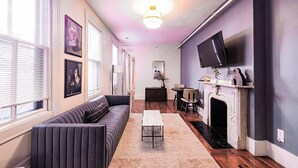 Ein Wohnzimmer mit einer Couch, einem Couchtisch, einem Kamin und einem an der Wand montierten Fernseher.