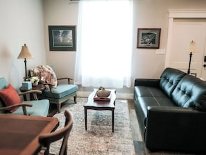 A living room with a sofa, chairs, a coffee table, and two framed pictures on the wall.
