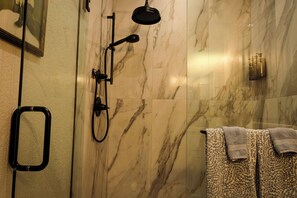 Un bagno con doccia, uno specchio chiuso in vetro e un portascopevoli con asciugamani decorati.