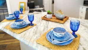 A kitchen counter with blue glassware and plates, a wooden tray with a plant, and a marble countertop. - Saint Jo Wine Country Barn - Walk to Blue Ostrich Winery (Saint Jo)