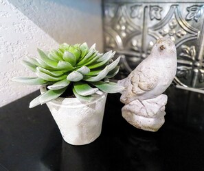 A succulent plant in a white pot and a white bird sculpture on a black surface.