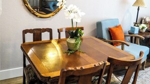 A dining area with a wooden table, chairs, a mirror, and a potted plant. - Saint Jo Wine Country Barn - Walk to Blue Ostrich Winery (Saint Jo)