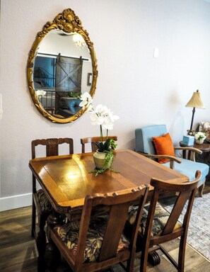 A dining area with a wooden table, chairs, a mirror, and a potted plant.