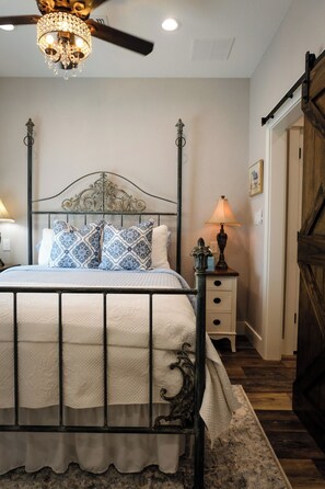 Una camera da letto con un letto a baldacchino, un lampadario, un comodino con una lampada e una porta in legno.