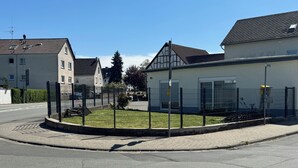 Um bairro residencial com casas, um quintal cercado e uma rua pavimentada.